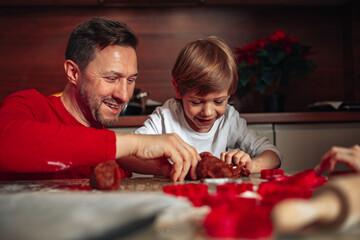 Son and dad. Little boy is happy to spend time with his father. Cookies are baked in kitchen at home. Happy moments of Christmas. People are having fun. Happy family.