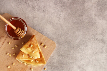 thin pancake with pine nuts and honey on a gray background
