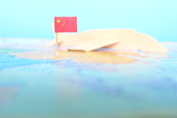 Selective focus of Chinese flag in blurry world map and wooden airplane model. China as travel and...