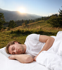 Man sleeping in bed and beautiful view of mountain landscape on background. Sleep well - stay...