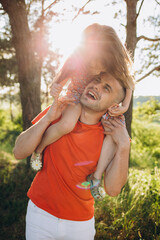 little girl is sitting on her father's shoulders in the summer in the park