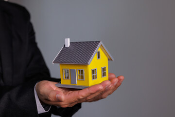 Businessman Hand holding home model, mortgage loan concept