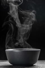 Bowl of hot steam of hot soup with smoke. black ceramic bowl on dark background. Hot food. Culinary, cooking, concept