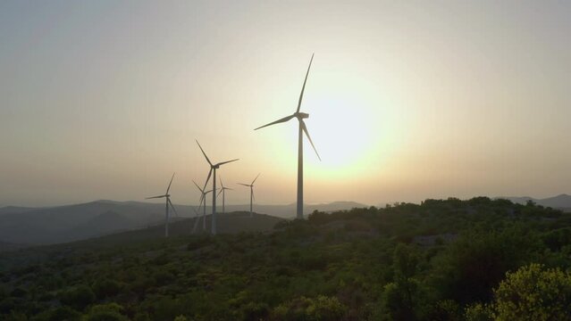Aerial view family mom and kids in the mountains near the windmills at sunset. People and the production of clean wind energy, travel in a beautiful landscape.