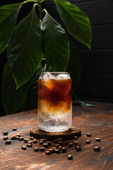 Cold espresso tonic. A highball glass filled with ice cubes, tonic soda water, coffee beans around, wooden background - 510759326