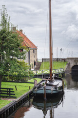 Traditional Dutch fishing boat with picturesque fishermen's cottages in the background in the historic town of Enkhuizen, The Netherlands. - 510759518