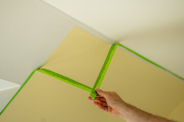 Painter removes masking tape and creates a sharp border between a yellow and white painted part of...