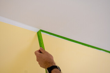 Nach dem Streichen einer Wand wird Malertape abgezogen, um eine scharfe Farbkante zwischen einem...