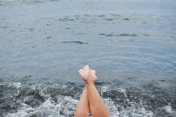 two crossed legs against the background of a sea wave
