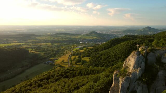 Aerial footage of reverse flight alongside cliff ledge with beautiful mountain panorama in the Swabian Alps in Southern Germany at sunset