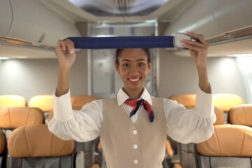 Beautiful Asian airline flight attendance demonstrates flight safety instruction by using seat belt before airplane takeoff.