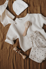 Stylish elegant newborn baby clothes and accessories on neutral brown linen cloth. Sweater,...