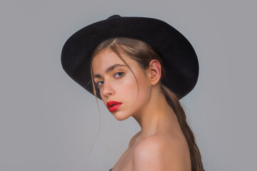 Young woman with make up and black hat in black studio. Fashion portrait of female model with red lips.