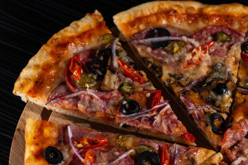 bright pizza on a dark table. pizza with olives and red pepper