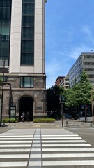 Street crossing at Tokyo Station Marunouchi area, vintage look office buildings and modernist buildings contrast, year 2022 June 13th, sunny weekday Japan