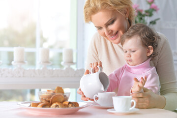 Obraz na płótnie Canvas Mom and daughter eat breakfast and drink tea