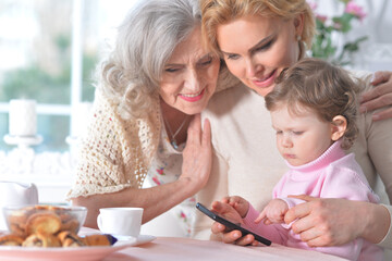Little girl with her mother and grandmother use the phone