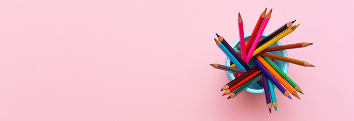 Colored wooden pencils on pink background, education concept