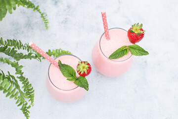 Top view of strawberry banana smoothie or smoothie garnished with strawberry berry and mint leaf on...