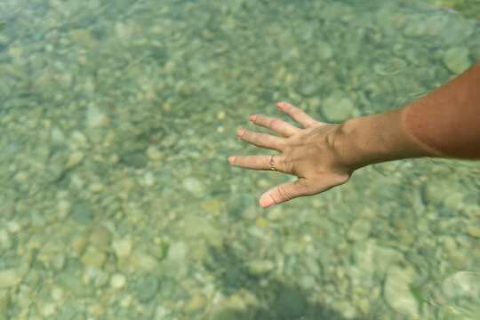 A female hand moving in the turquoise water of a natural pool