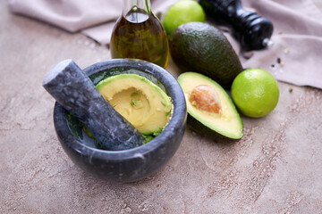 making guacamole - fresh sliced avocado in marble mortar on grey concrete table