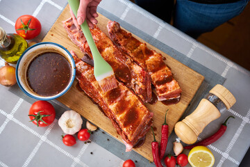 Brushing Pork Ribs with marinade sauce on Wooden Cutting Board - obrazy, fototapety, plakaty