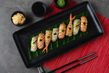 Sushi set of various products on a black stone plate. Blur background and selective focus