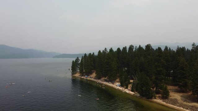 Drone shot of a beach on the shore of Payette Lake with the forest and mountains in the background. This 4K cinematic Idaho nature scene was filmed using a DJI Mini 2 drone.