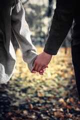 Close-up of a couple in love holding hands while walking. Selective focus, vertical. © Roman