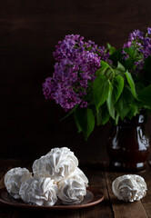 apple zephyr on a wooden background in a plate, in the background - a cup of coffee, lilac branches. French village morning over a cup of coffee with delicate marshmallows. rustic style