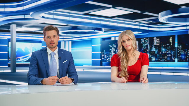 TV Live News Program: Two Presenters Reporting, Talking, Discuss Daily Events, Friendly Chat. Television Cable Channel Diverse Team Of Male And Female Anchors Talk. Newsroom Studio Concept