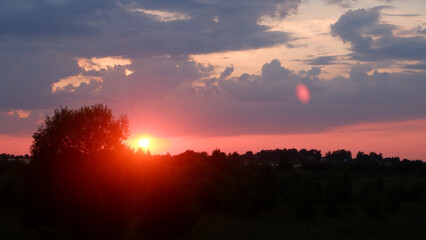 Rural landscape with field at sunset and village in the background. Vologda region