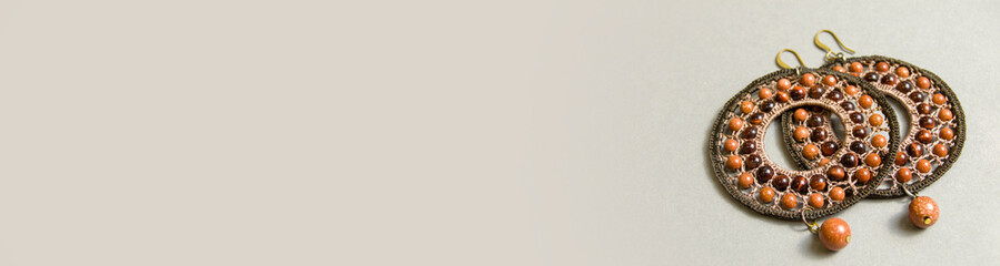 round braided jewelry with natural stones on a gray background. Banner for insertion into site. Place for text cope space. Horizontal image