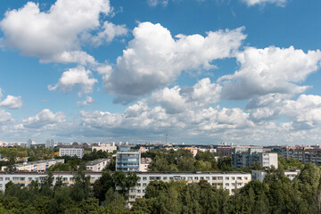 Bright beautiful white clouds against the midday blue sky over the city.