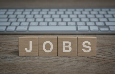 Jobs letter on wood block cubes on wooden table with modern computer keyboard, Business recruitment online concept