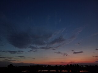 sunset in the village, blue sky, trees, clouds in the sky 