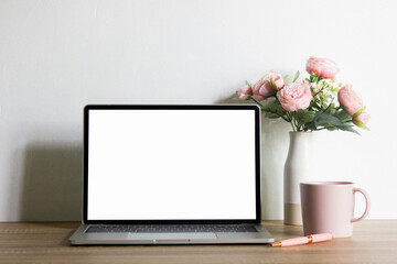 Mock up computer with pink flowers and coffee cup on table with natural light. 