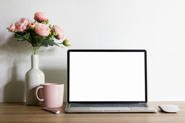 Mock up computer with pink roses and pink coffee mug with nature light. 
