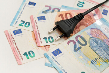 Power plug on euro banknotes. Cost of electricity and expensive energy concepts. Increasing consumption, energy crisis. Inflation. Price level are getting more expensive annually.