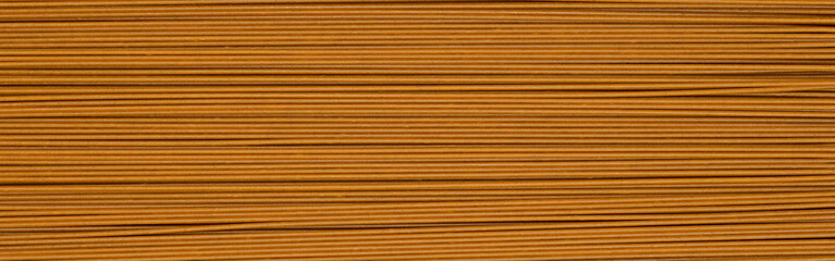 brown long raw spaghetti background. buckwheat noodles