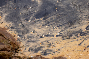 Black sand beach with normal sand mixed with sea water.