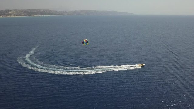 Tourists enjoy colorful parasail ride behind tour boat in blue water