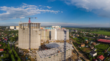 Industrial building site. skyscrapers under construction on clear blue sky background with two crane