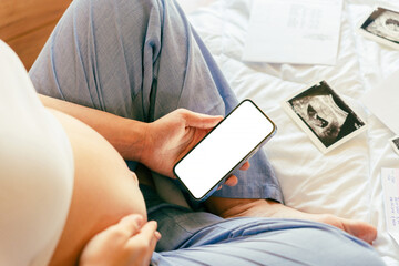 Pregnancy smartphone mockup. Pregnant woman holding smartphone. Mobile pregnancy online maternity application mock up. Concept of pregnancy, maternity, expectation for baby birth. - obrazy, fototapety, plakaty