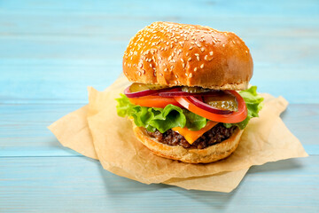 Tasty burger on light blue wooden table. Fast food
