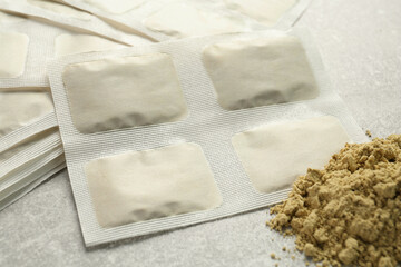Mustard powder and plasters on light grey table, closeup