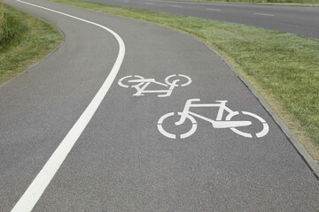 Bicycle lane with white sign painted on asphalt near sidewalk