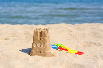 Sand castle and child plastic toys on beach near sea