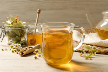 Freshly brewed tea and dried herbs on white wooden table