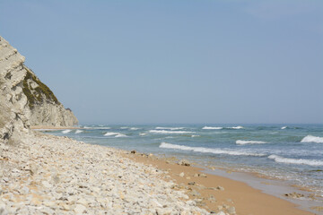 Fototapeta na wymiar Beautiful view of sandy beach with rocks and sea. Summer vacation